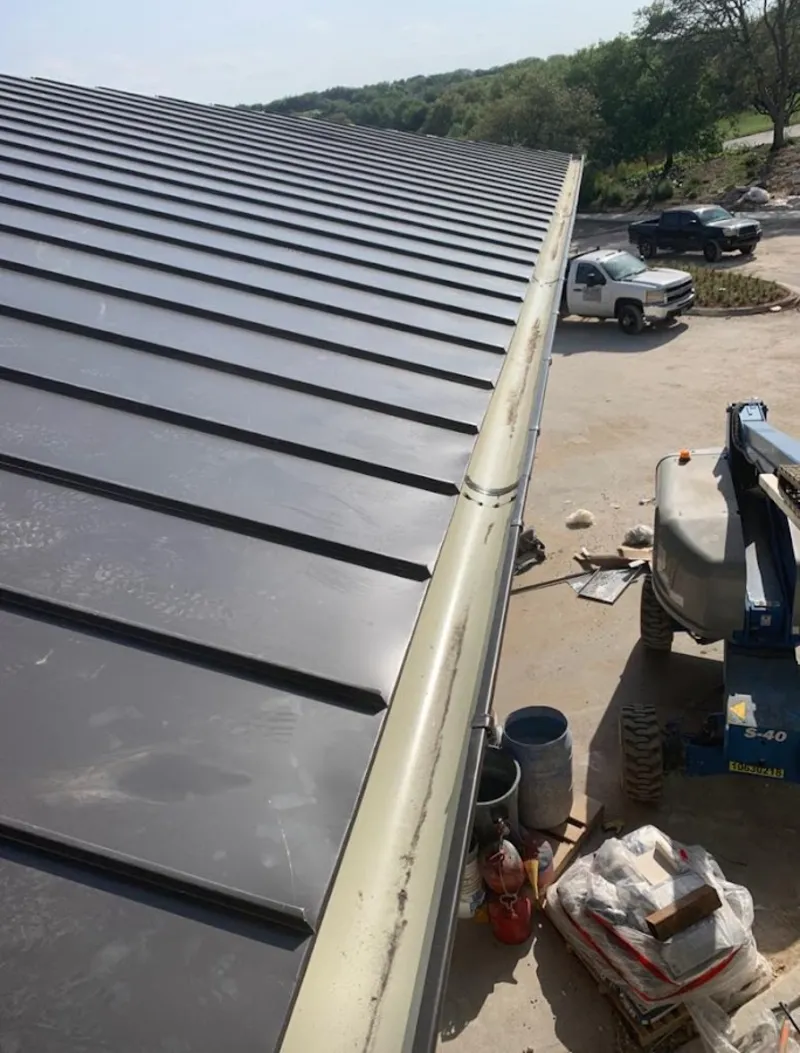 Standing seam panel and gutter detail on a metal roofing jobsite in Adel